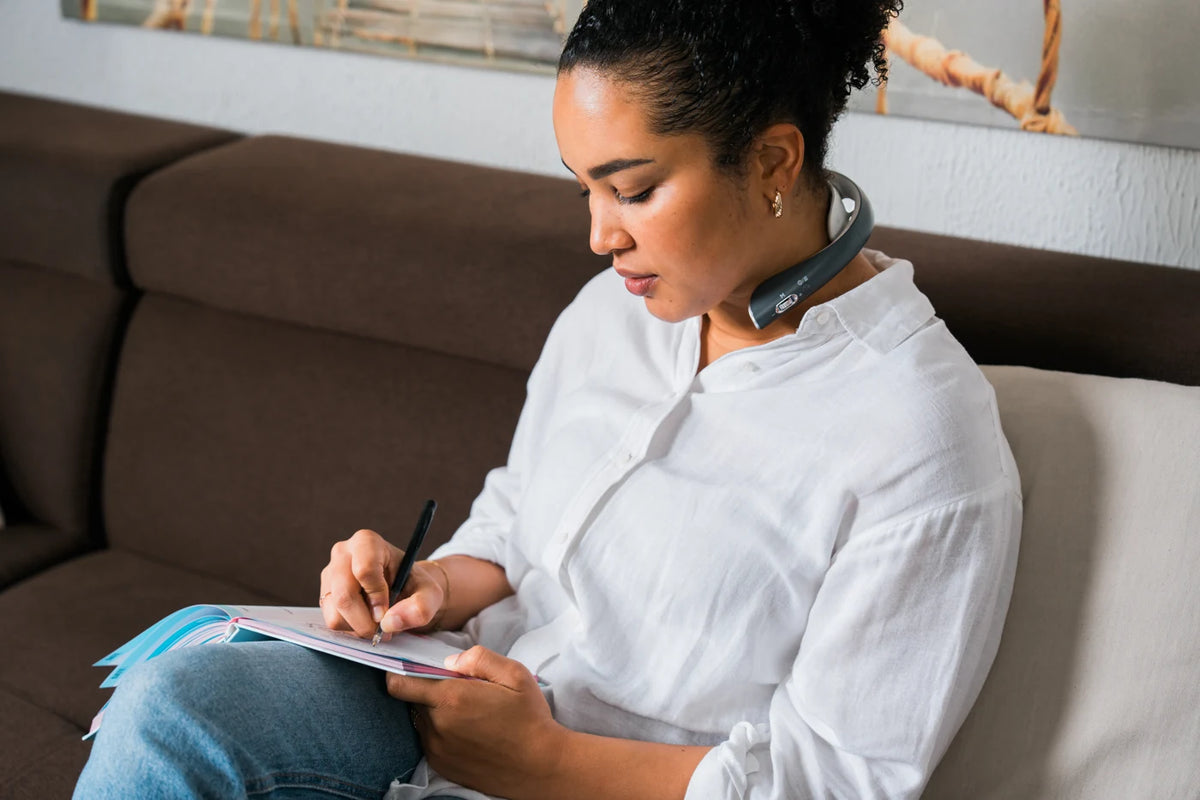 Woman writing in a notebook on a sofa, wearing Slate Grey Professional X